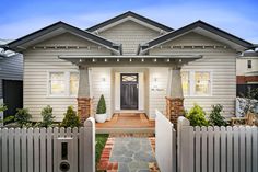 a house with a white picket fence in front of it and a black door on the other side