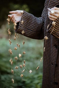 a person wearing a suit and holding some gold stars on their necklaces while standing in the grass