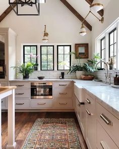 a kitchen with white cabinets and wood flooring has a rug on the floor in front of the stove