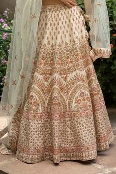 Ivory raw silk lehenga with attached cancan and all-over floral motifs, 8 silken threads and cutdana- dabka work. Comes with zardozi embroidered padded blouse and two dupattas.
Component: 4
Embroidered
Neckline: Leaf
Sleeve Length: Half
Fabric: Lehenga and Blouse: Raw Silk;  Dupatta: Net; Lining: Cotton Shantoon
Color: White
Tassel tie-up back - Aza Fashions Cream Bollywood Lehenga With Floral Embroidery, White Embroidered Raw Silk Gown, Cream Floor-length Sets With Intricate Embroidery, Off White Raw Silk Set With Intricate Embroidery, White Raw Silk Gown With Dupatta, Cream Raw Silk Dress With Intricate Embroidery, Cream Embroidered Raw Silk Sets, Festive Cream Lehenga With Floral Embroidery, White Floral Embroidery Raw Silk Lehenga