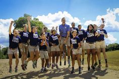 a group of young people standing on top of a dirt road next to each other