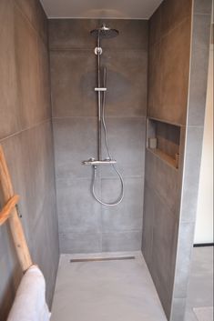 a walk in shower sitting inside of a bathroom next to a wooden ladder on the wall