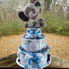 a diaper cake that has an elephant on top and blue ribbon around the bottom