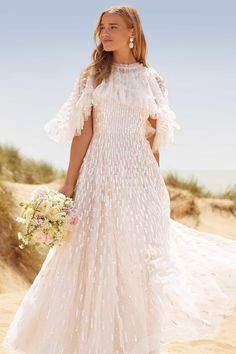 a woman in a wedding dress standing on the beach