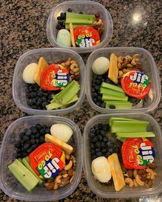 four plastic containers filled with food on top of a granite countertop next to a marble counter