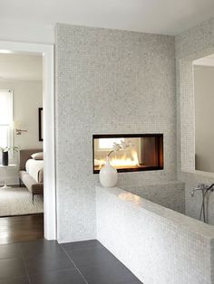 a bathroom with a fireplace in the middle of it's wall and tiled floor