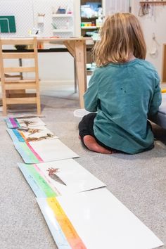 a little boy sitting on the floor next to some cut out paper