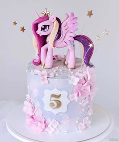 a pink and purple cake with a pony on top that has stars around the edges