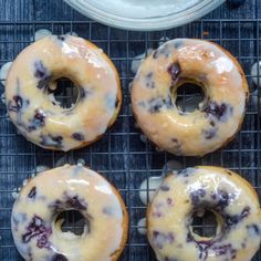 four blueberry donuts sitting on top of a cooling rack