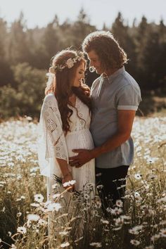 a man and woman standing in a field with wildflowers