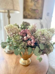 a vase filled with flowers sitting on top of a wooden table next to a lamp