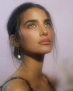 a close up of a person wearing earrings and looking off to the side with her eyes closed