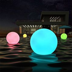 three glowing balls floating in the water near a house at night with stars above them