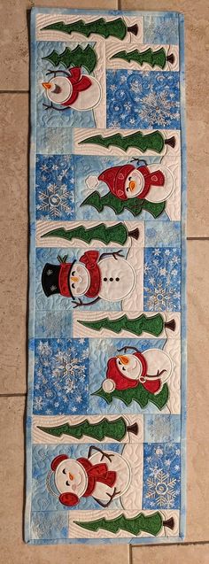 a quilted wall hanging with snowmen on it