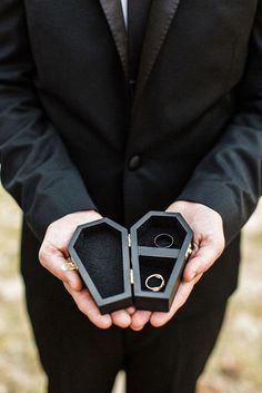 a man in a suit holding an open ring box