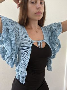 a woman is wearing a blue crochet shrugr