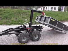 a trailer with two large wheels attached to the front and rear ends, parked on gravel