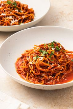 two white bowls filled with spaghetti and sauce