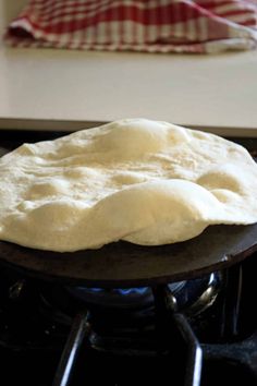 an uncooked pizza sitting on top of a wooden table next to a stove