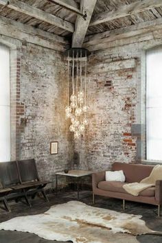 a living room filled with furniture and a chandelier hanging from the ceiling next to two windows