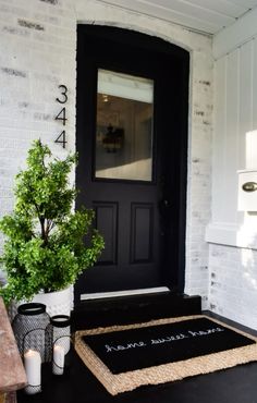 a black front door with a welcome mat and two candles on the floor next to it