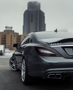 the rear end of a mercedes cla parked in front of a cityscape