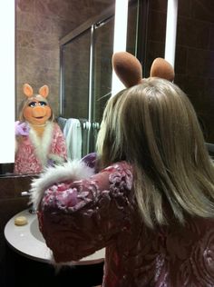 a woman is brushing her hair in front of a mirror with the character miss piggy on it