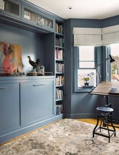 a room with blue walls and bookshelves in the corner, an area rug on the floor