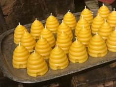 many yellow candles are arranged on a metal tray