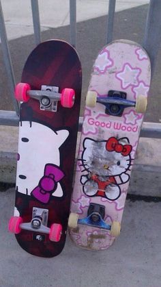 two skateboards with hello kitty designs on them sitting next to each other in front of a gate