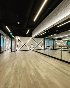 an empty room with wooden floors and mirrors