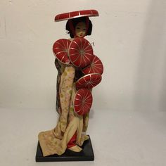 a figurine is holding two red umbrellas on it's head and wearing a kimono