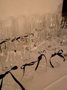 many empty wine glasses on a table with black ribbon around the edges and bows tied to them