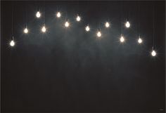 a bunch of lights that are hanging from the ceiling in front of a black wall