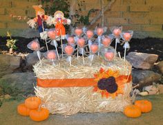 an arrangement of lollipops and candy on sticks in a hay carton