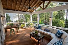 a covered porch with couches and tables on it's sides, surrounded by greenery