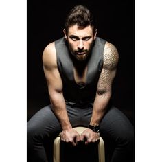 a man with tattoos sitting on a stool