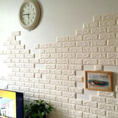 a white brick wall with a clock on the side and pictures hanging on the wall