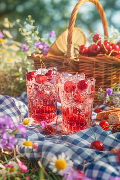 two glasses filled with cherries sitting on top of a blue and white checkered table cloth