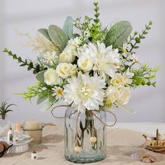 a glass vase filled with white flowers on top of a table next to other items