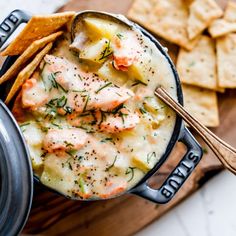 a close up of a bowl of food with crackers on the side next to it