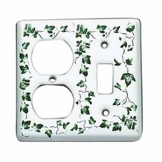 a white switch plate with green leaves on it's side and one outlet in the middle