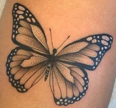 a black and white butterfly tattoo on the side of a woman's thigh,