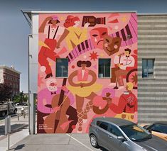 a large colorful mural on the side of a building next to a parking lot with cars parked in front of it