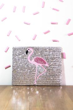 a pink flamingo purse sitting on top of a wooden floor next to confetti