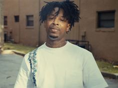 a man with dreadlocks is standing in front of a building and looking at the camera