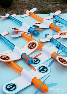 an assortment of paper airplanes on a blue tablecloth with orange and white trims