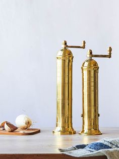 two golden faucets sitting on top of a wooden table next to an egg