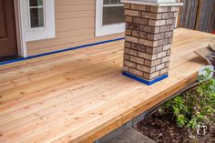 a wooden deck with blue tape around it and a brick chimney on the top corner