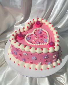 a pink heart shaped cake with white frosting and sprinkles on it